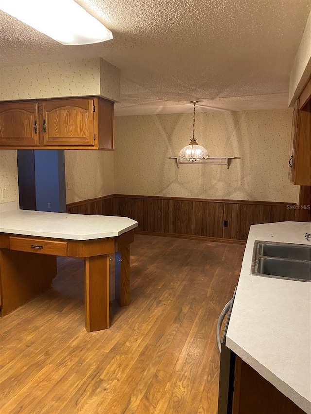 kitchen featuring kitchen peninsula, sink, a textured ceiling, and pendant lighting