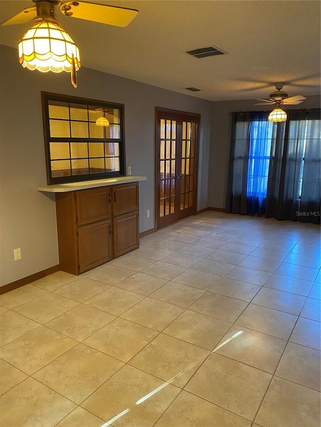 tiled empty room featuring a textured ceiling, ceiling fan, and french doors