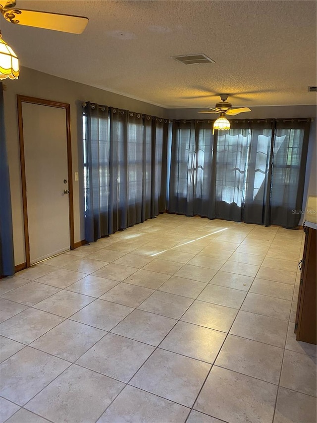 interior space with ceiling fan, a textured ceiling, and light tile patterned floors