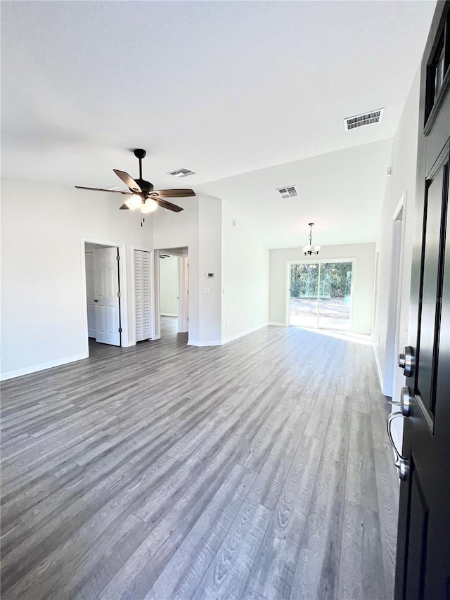 unfurnished living room featuring dark wood-type flooring and ceiling fan with notable chandelier