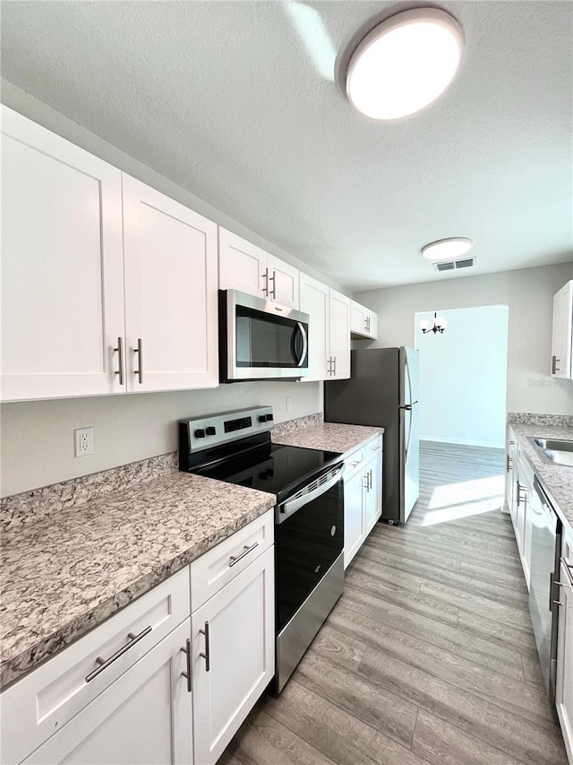 kitchen with light stone countertops, white cabinets, and appliances with stainless steel finishes