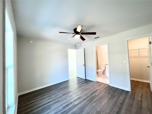 unfurnished bedroom with ceiling fan, ensuite bathroom, a spacious closet, a closet, and dark hardwood / wood-style flooring