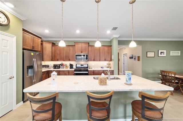 kitchen featuring a kitchen breakfast bar, decorative light fixtures, sink, an island with sink, and stainless steel appliances