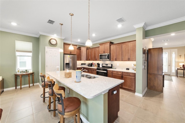 kitchen featuring decorative light fixtures, stainless steel appliances, sink, a center island with sink, and a breakfast bar area