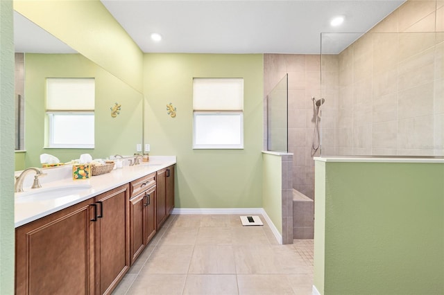 bathroom featuring tile patterned floors, vanity, a tile shower, and a healthy amount of sunlight