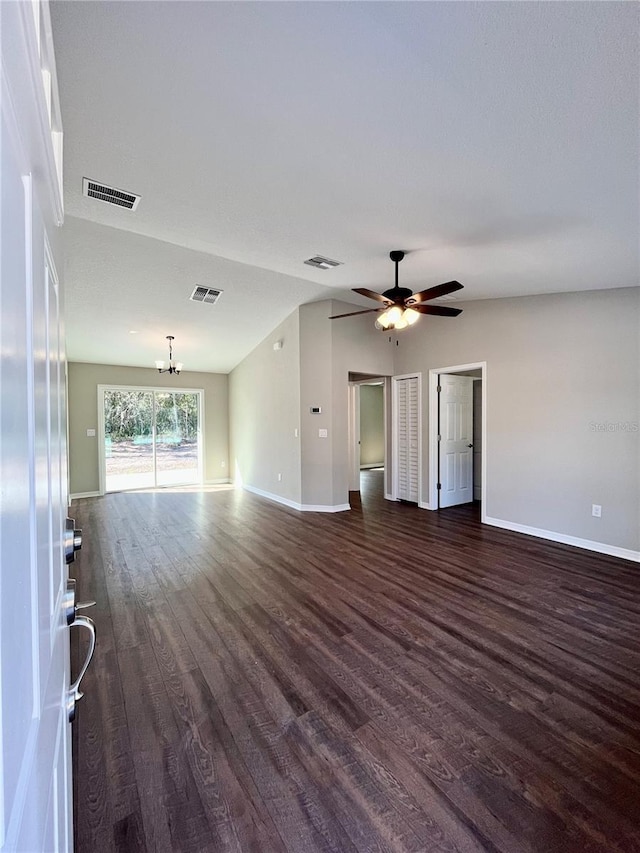 empty room featuring vaulted ceiling, dark hardwood / wood-style flooring, and ceiling fan with notable chandelier