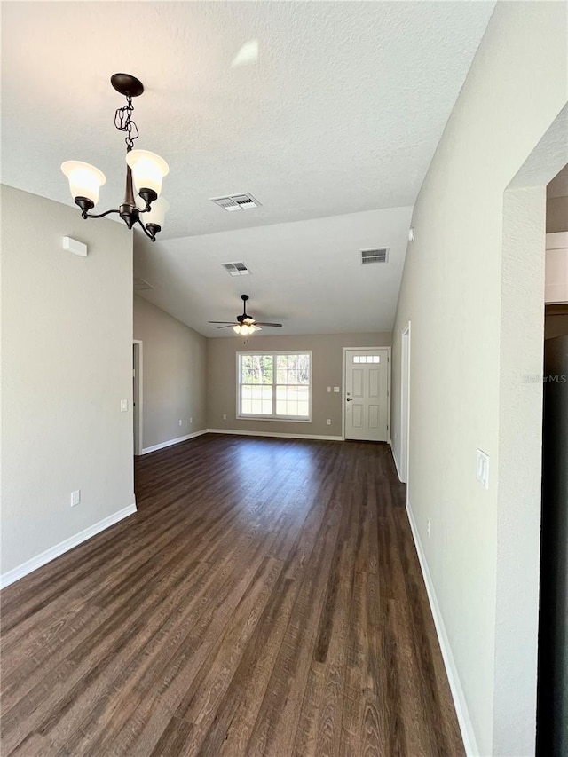 unfurnished living room with lofted ceiling, dark hardwood / wood-style floors, ceiling fan with notable chandelier, and a textured ceiling