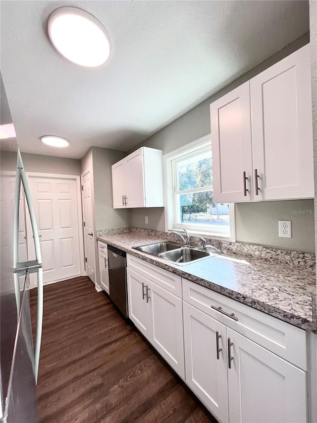 kitchen with dark hardwood / wood-style flooring, a textured ceiling, stainless steel dishwasher, white cabinets, and sink