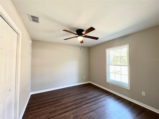 unfurnished room with ceiling fan, dark wood-type flooring, and a textured ceiling