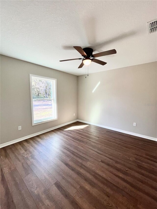 empty room with a textured ceiling, ceiling fan, and dark hardwood / wood-style flooring