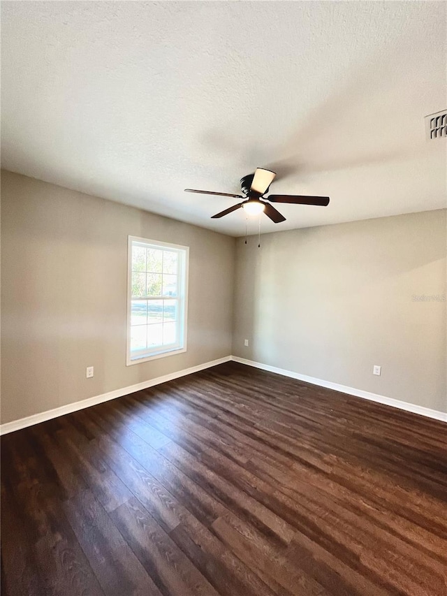 spare room with a textured ceiling, ceiling fan, and dark hardwood / wood-style flooring