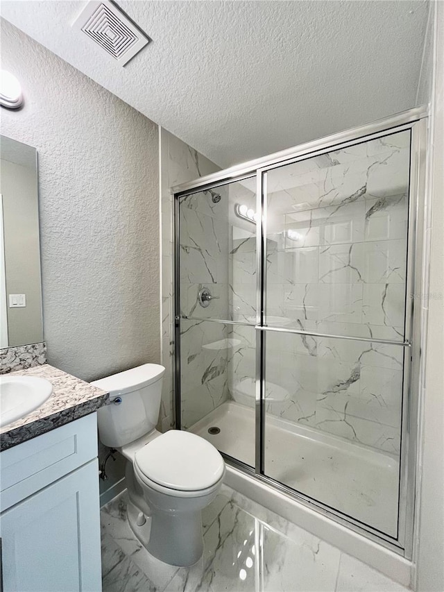 bathroom with toilet, vanity, an enclosed shower, and a textured ceiling