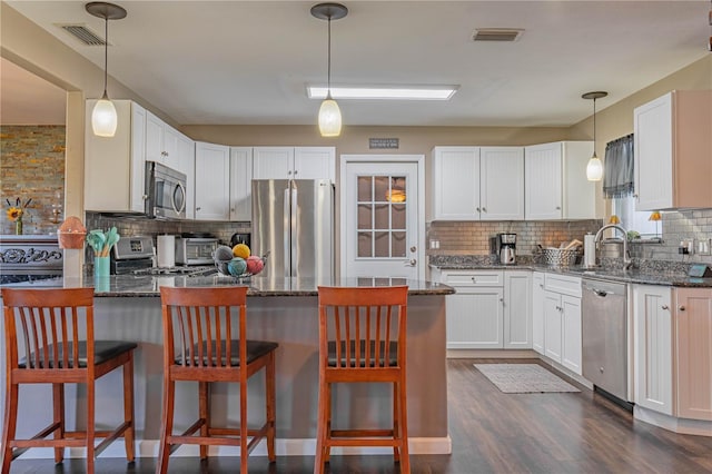 kitchen with a kitchen breakfast bar, white cabinets, and appliances with stainless steel finishes