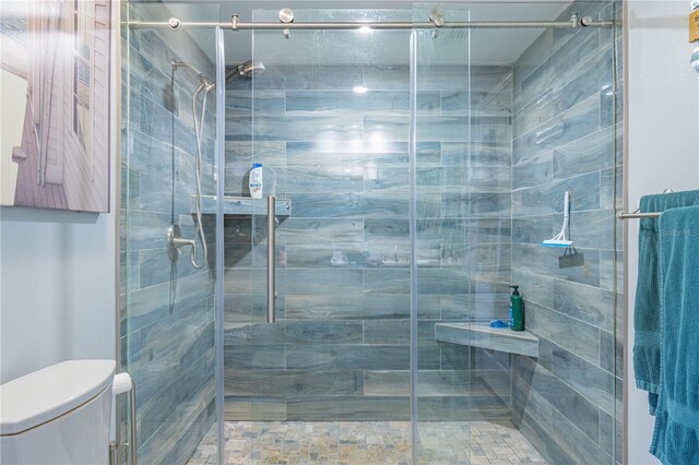 bathroom featuring toilet and a shower with shower door