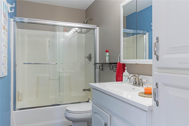 full bathroom with vanity, combined bath / shower with glass door, and toilet