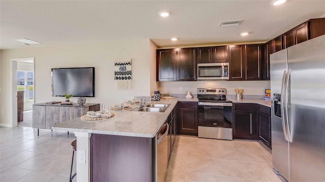 kitchen featuring light tile patterned floors, kitchen peninsula, appliances with stainless steel finishes, dark brown cabinets, and sink