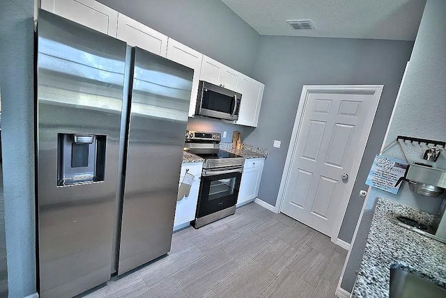 kitchen with stone countertops, white cabinetry, and appliances with stainless steel finishes