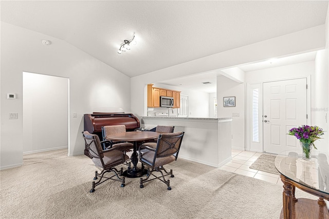 dining room featuring light carpet, lofted ceiling, and a textured ceiling