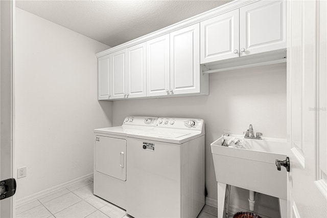 laundry room featuring light tile patterned floors, sink, washer and clothes dryer, cabinets, and a textured ceiling