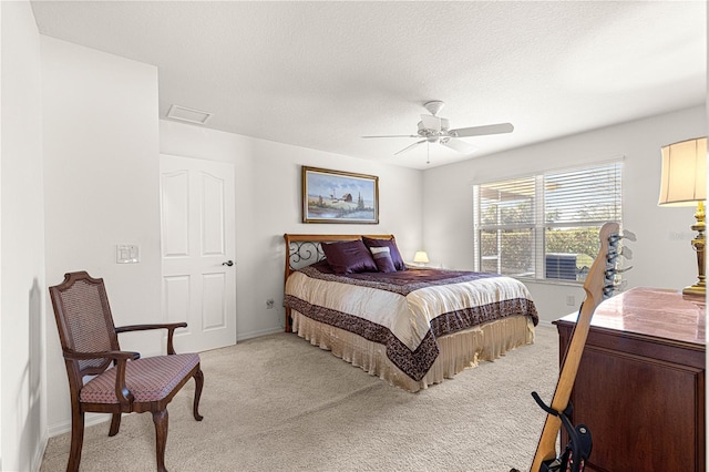 carpeted bedroom featuring ceiling fan and a textured ceiling