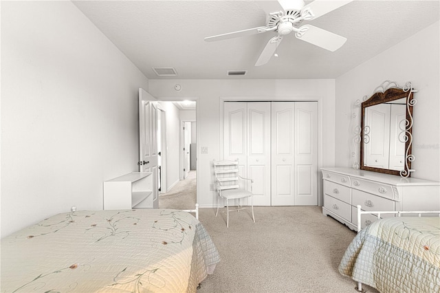 bedroom with ceiling fan, a closet, light carpet, and a textured ceiling