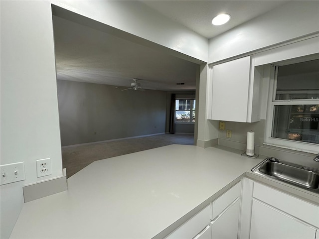 kitchen featuring ceiling fan, white cabinetry, and sink