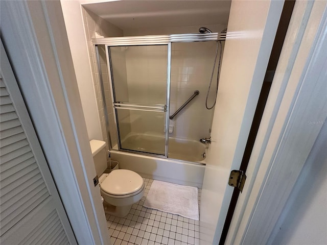 bathroom with tile patterned floors, bath / shower combo with glass door, and toilet