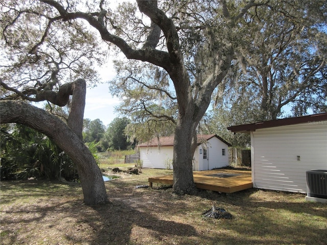 view of yard featuring an outbuilding, central AC, and a wooden deck