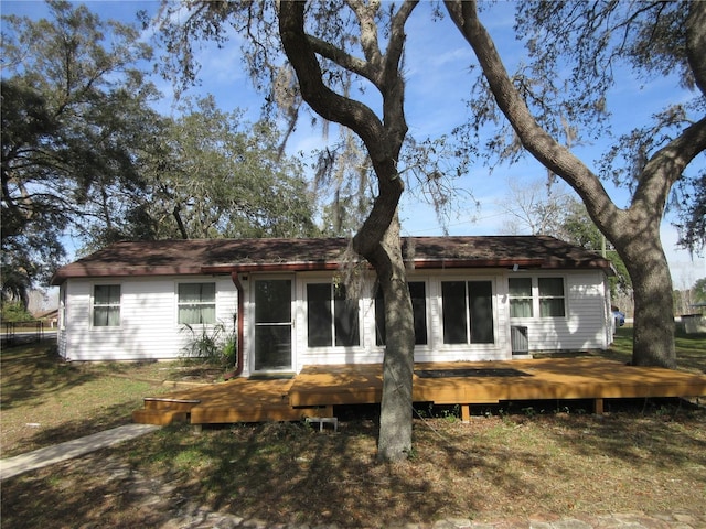 rear view of house with a deck and a lawn