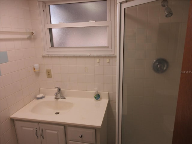 bathroom with a tile shower, tile walls, and vanity