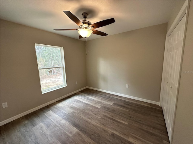 unfurnished bedroom featuring ceiling fan, a closet, and dark wood-type flooring