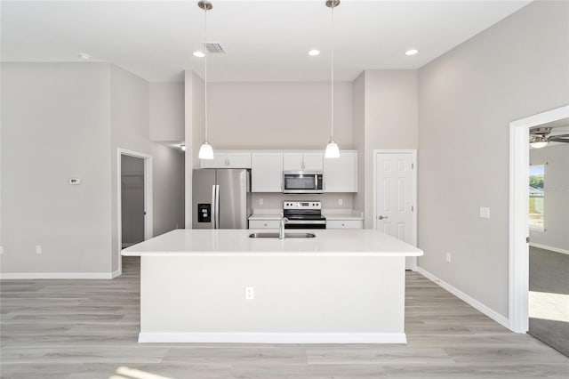 kitchen with stainless steel appliances, a kitchen island with sink, hanging light fixtures, and white cabinets