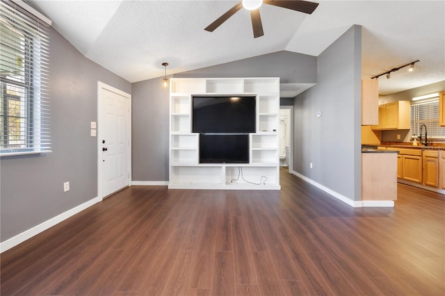 unfurnished living room featuring ceiling fan, vaulted ceiling, dark hardwood / wood-style floors, and sink