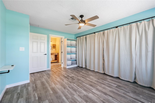 unfurnished bedroom with ceiling fan, a textured ceiling, and hardwood / wood-style flooring