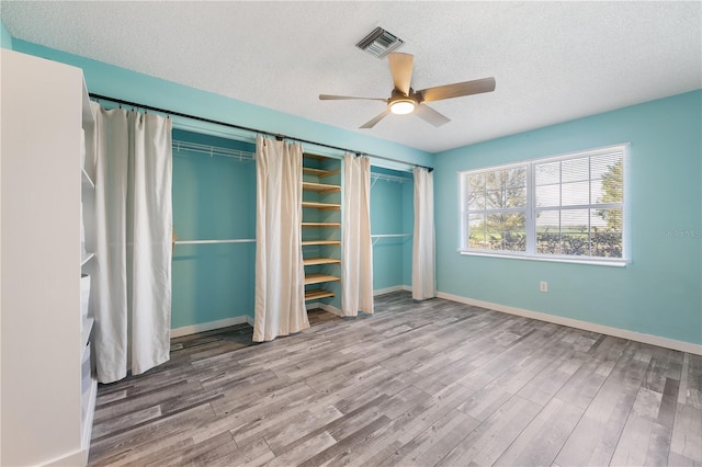 unfurnished bedroom with a textured ceiling, ceiling fan, and wood-type flooring