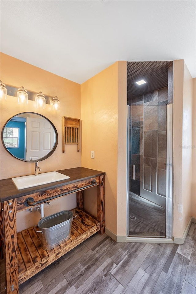 bathroom with an enclosed shower, sink, and hardwood / wood-style floors