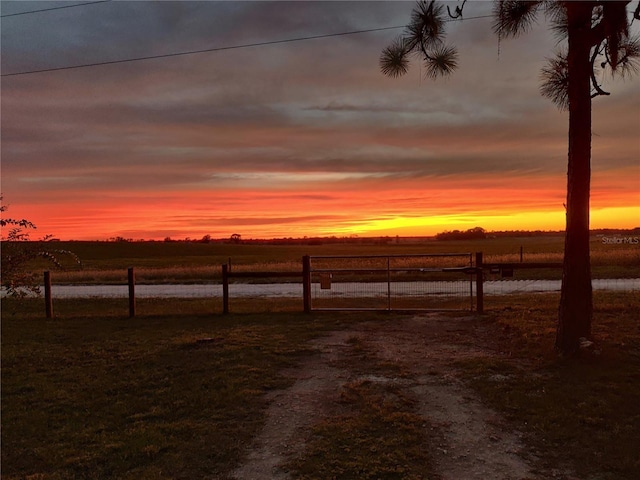 yard at dusk featuring a rural view