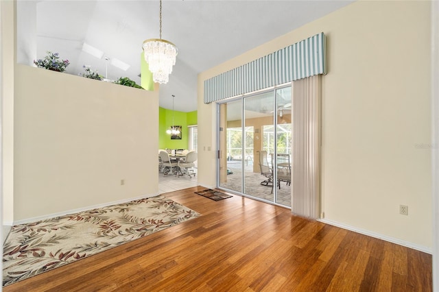 empty room featuring an inviting chandelier, light hardwood / wood-style flooring, and a high ceiling