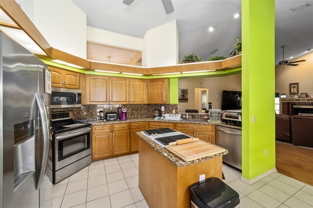 kitchen with appliances with stainless steel finishes, a center island, light tile patterned floors, and kitchen peninsula