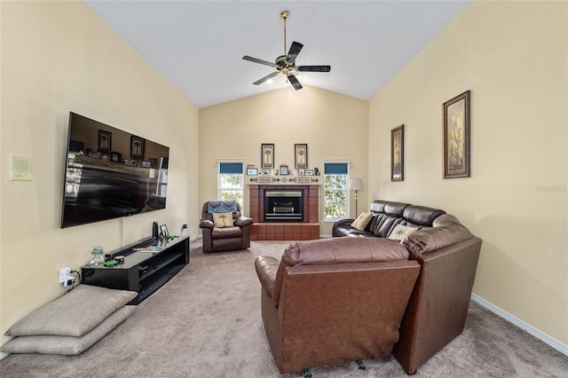 carpeted living room featuring a tile fireplace, vaulted ceiling, and ceiling fan