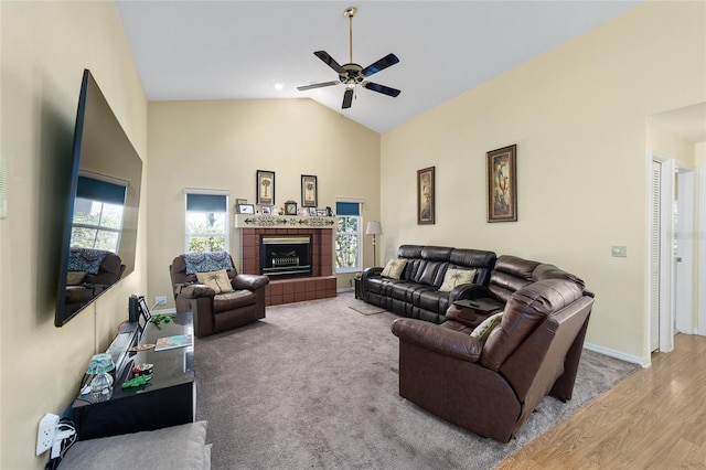 living room with a tile fireplace, ceiling fan, high vaulted ceiling, and light hardwood / wood-style floors