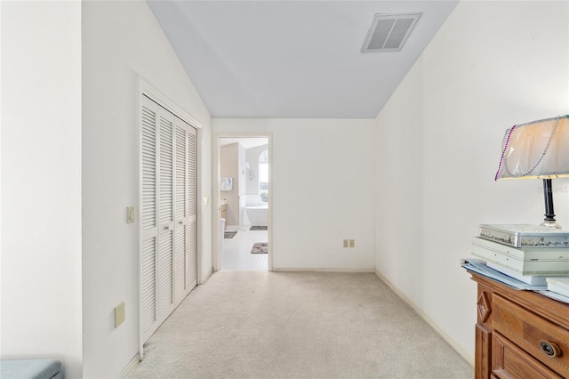 corridor with lofted ceiling and light colored carpet