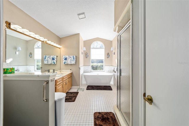 bathroom featuring vaulted ceiling, plus walk in shower, tile patterned flooring, vanity, and a textured ceiling