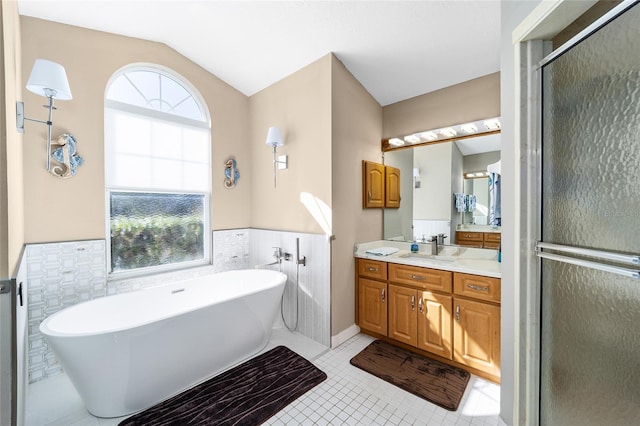 bathroom with shower with separate bathtub, lofted ceiling, tile walls, tile patterned flooring, and vanity