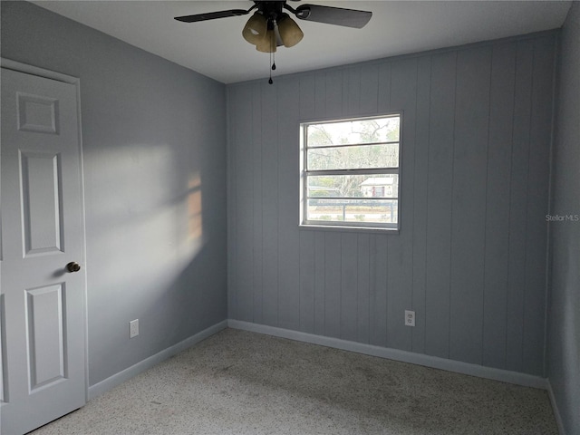 unfurnished room with ceiling fan and wooden walls