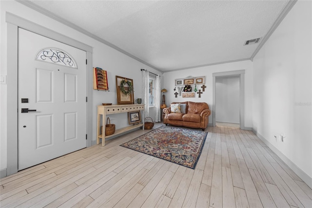 living room with a textured ceiling, crown molding, and light wood-type flooring