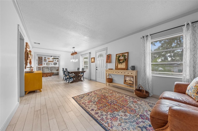 living room with ornamental molding, a textured ceiling, and light hardwood / wood-style floors