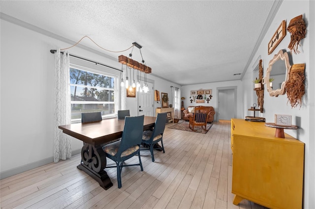 dining area with light hardwood / wood-style floors, a textured ceiling, and crown molding