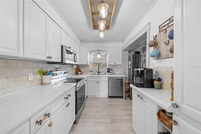 kitchen featuring white cabinets, appliances with stainless steel finishes, decorative light fixtures, tasteful backsplash, and sink