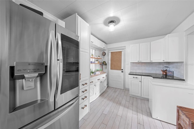 kitchen with light hardwood / wood-style floors, white cabinets, stainless steel fridge with ice dispenser, and tasteful backsplash